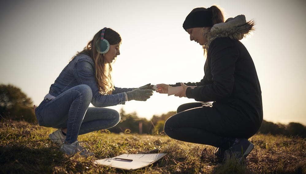 To elever sidder på hug overfor hinanden udenfor