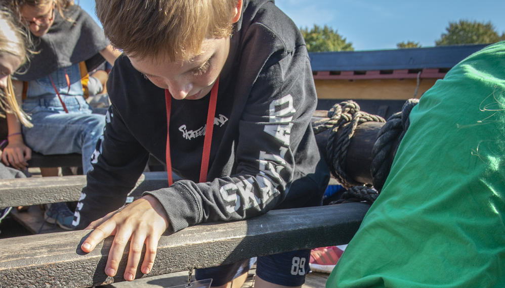 Elev undersøger vikingeskib på Vikingeskibsmuseet