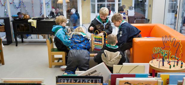 En gruppe børn læser bøger sammen på biblioteket