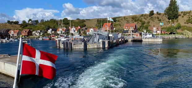 Båd der sejler væk fra den svenske kyst med et dansk flag