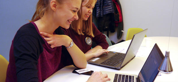 To piger sidder med hver deres bærbare computer og arbejder