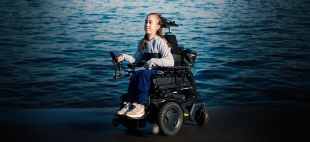 En ung kvinde i kørestol ude ved havet