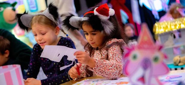 To børn sidder med hundeøre på og klippe-klistrer i en kreativ hundesalon-workshop