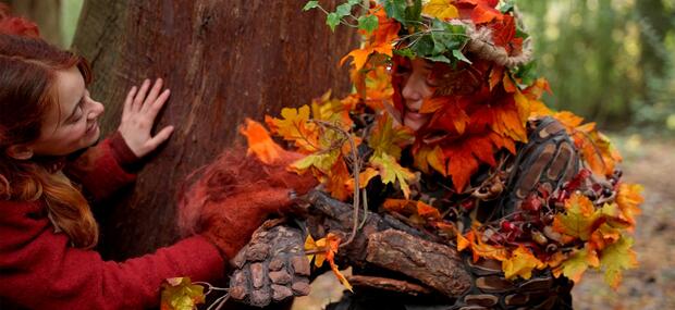 En kvinde klædt ud som et træ i skoven.